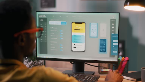 Developer analyzing app interface options and settings on a computer monitor for choosing the tech stack.
